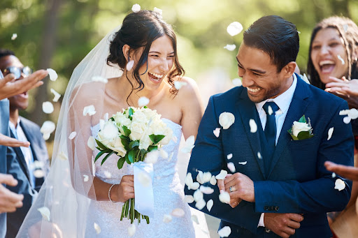 Guests throw confetti over the bride and groom as they walk past after their wedding ceremony. Joyful young couple celebrating their wedding day and embarking on their estate planning and marriage journey. 