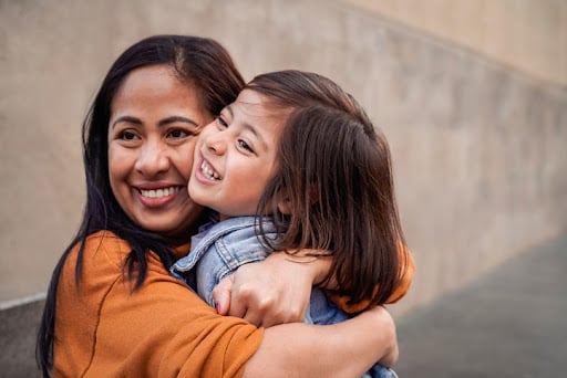 A mother and a young child embrace. Parents of young children should learn about 529 College savings plans as part of their college saving planning.