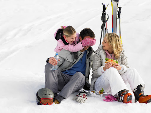 A young family with skis sitting in the snow. Smart Asset