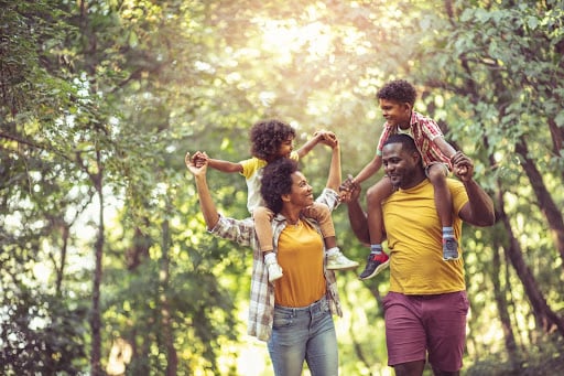 A black family with man and wife and kids hike on a forested trail. Trusts for Estate Planning