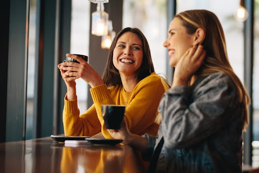 Two female friends sitting at a cafe having coffee. Here are some things to consider when choosing a wealth manager.