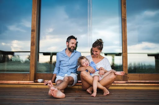 Purchasing a second home is possible with strategic vacation property planning. A family sits on the deck of their vacation home.