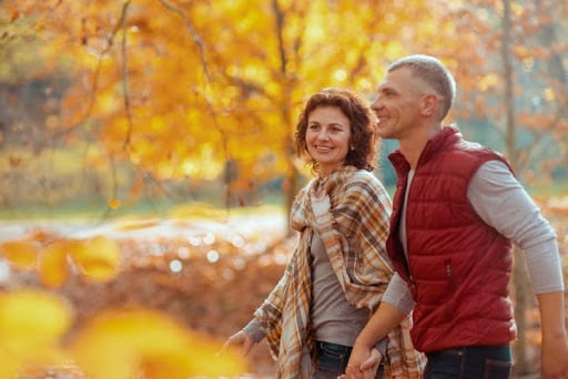 You don’t have to make decisions on your own when it comes to adjusting your wealth portfolio in response to market cycles. A couple walks through a park on an autumn day.