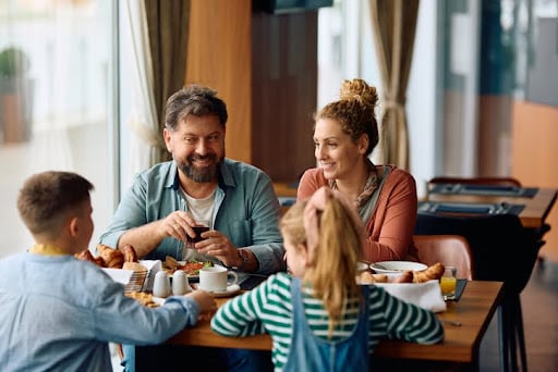 Preparing your wealth for life’s major changes. Parents enjoying breakfast time with their kids in a hotel.