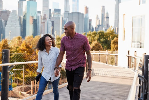 Couple Visiting New York With Manhattan Skyline In Background. Financial Planning