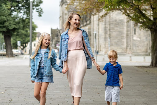 A mother holds hands with her daughter and son as they stroll through a park. Learning how to protect and raise your credit score is one of those important life lessons that a lot of us were never actually taught.