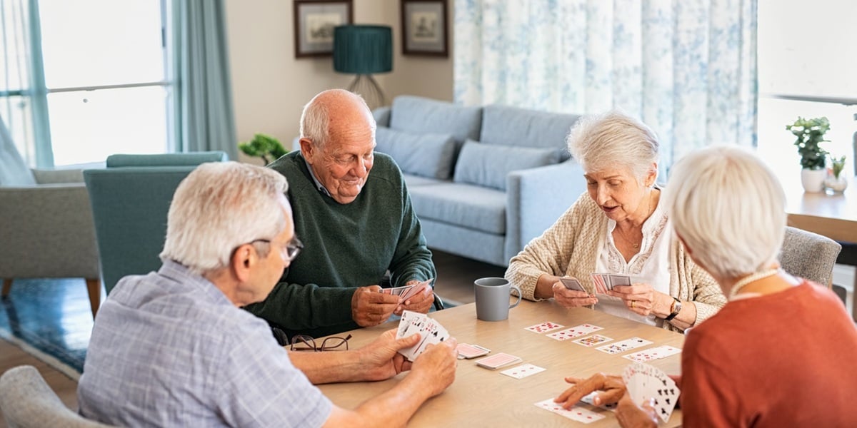 Private equity ownership in senior housing. Senior friends playing game of cards together