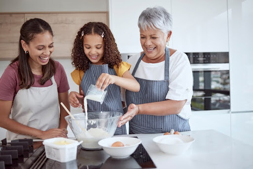 Mother, daughter and grandmother baking together in a kitchen. With effective wealth management, you can have the means to support aging parents in their later years.